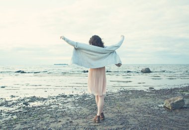 Mavi deniz ve gökyüzü arka plan üzerinde yürüyen güzel genç kadın