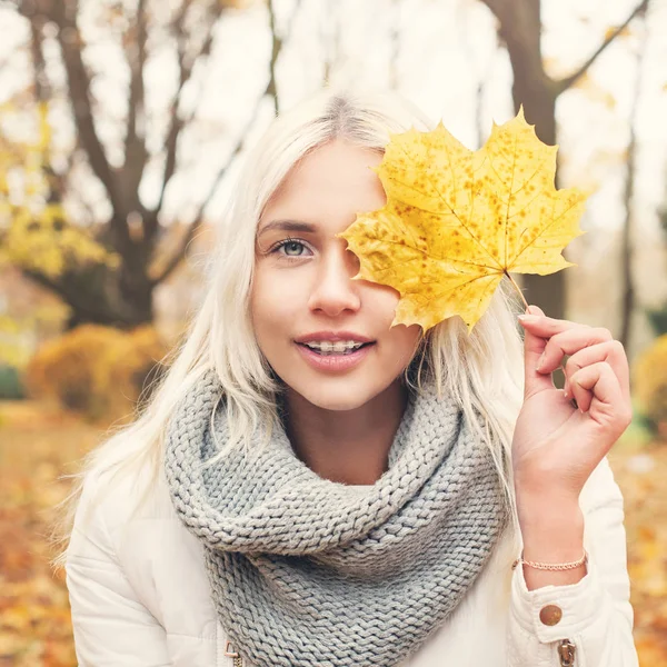 Amistosa mujer rubia modelo de moda celebración de hoja de otoño —  Fotos de Stock