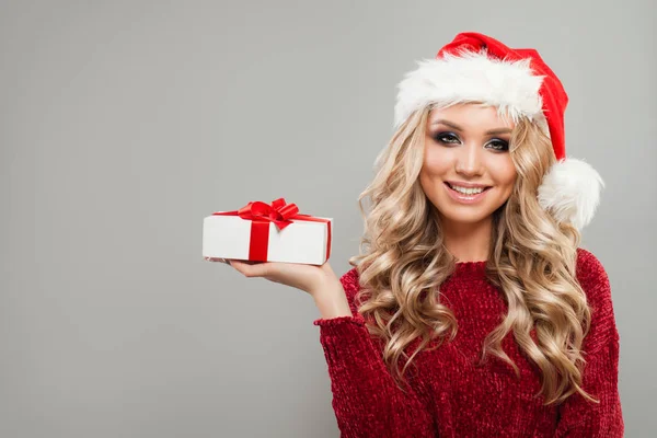 Vánoční žena nosí Santa klobouk znázorňující bílá vánoční dárek — Stock fotografie
