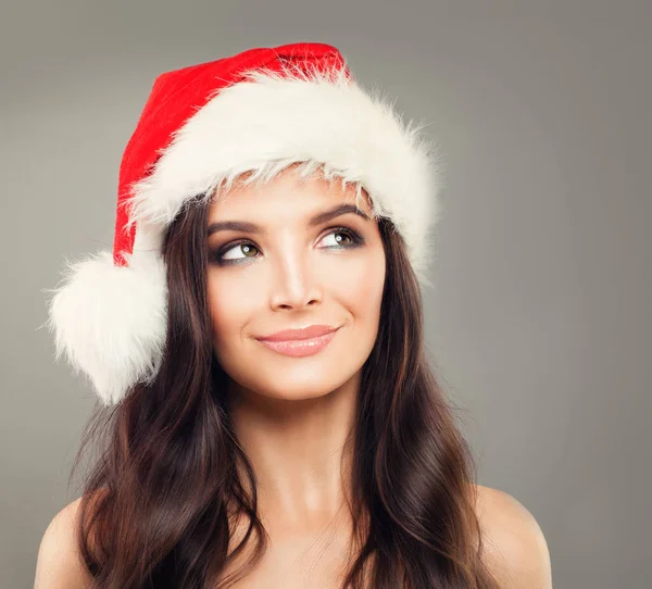 Feliz Navidad Modelo Mujer en Santa Sombrero sonriendo y mirando hacia arriba . —  Fotos de Stock