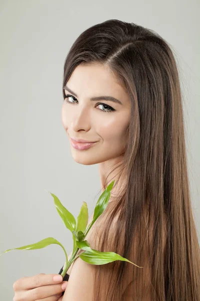 Joven mujer sana sosteniendo hojas de bambú verde. Cuidado del cabello —  Fotos de Stock