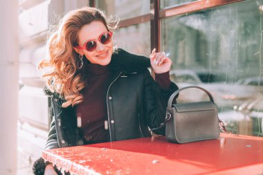 Mutlu genç kadın oturan Street Cafe, Street style
