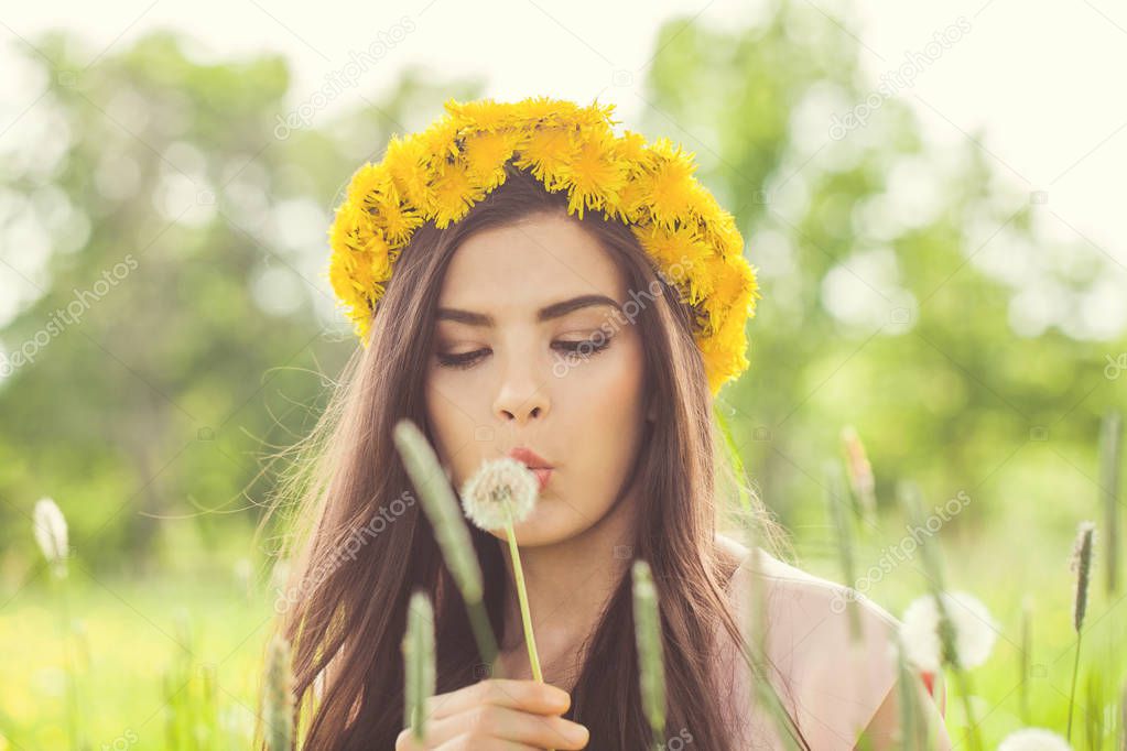 Summer woman blowing on dandelion flowers