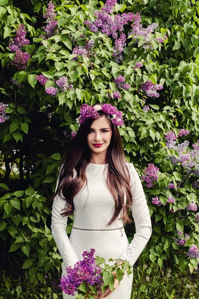 Ung brunett kvinna med lila blommor utomhus — Stockfoto