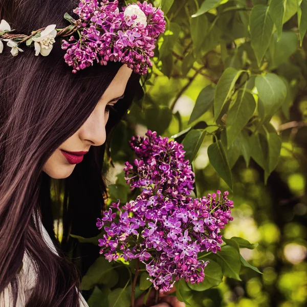 Schöne Frau im Freien auf grünen Blättern und lila Blüten — Stockfoto