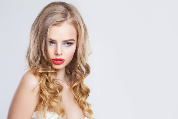 Sensual blonde woman with long healthy curly hair and red lips