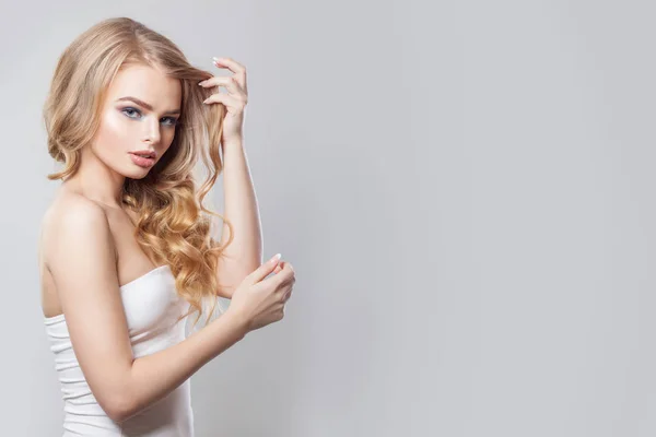 Blonde woman showing her hair on white background — Stockfoto