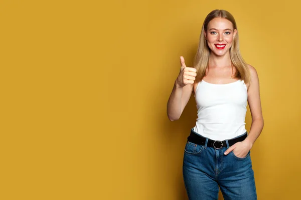 Felice giovane donna mostrando pollice su sfondo giallo . — Foto Stock