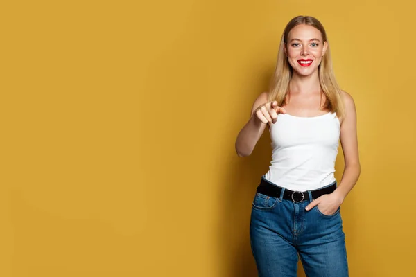 Glückliche Frau zeigt auf leuchtend gelben Hintergrund. Positive Emotionen — Stockfoto