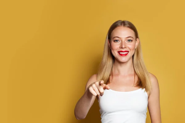 Hübsche Frau zeigt auf leuchtend gelben Hintergrund — Stockfoto