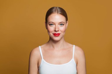 Sarı arka planda gülümseyen genç model kadın.