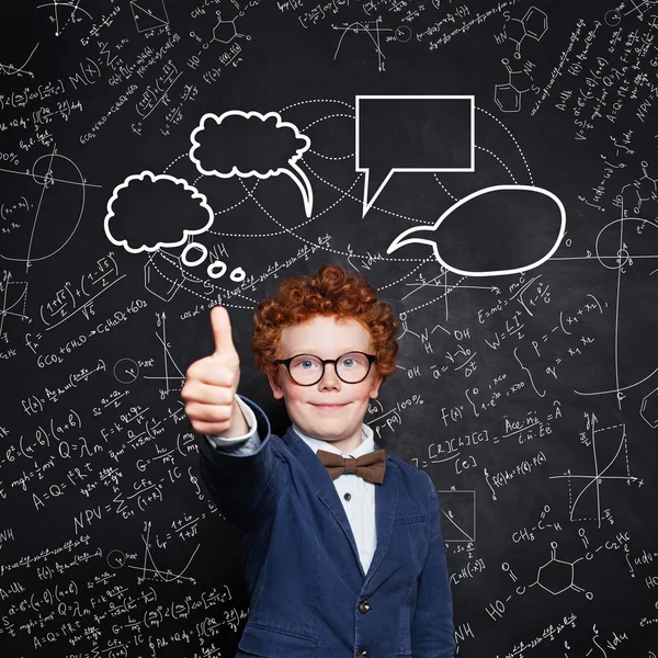 Portrait of smiling smart boy on blackboard background — Stock Photo, Image