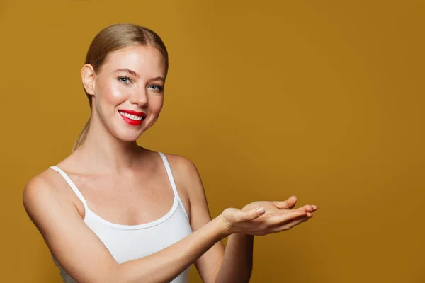 Mulher bonita sorrindo e segurando a mão aberta vazia — Fotografia de Stock