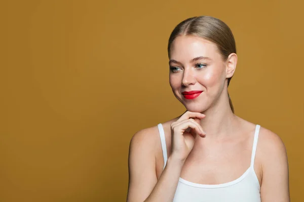 Schöne Frau schaut beiseite auf gelbem Hintergrund — Stockfoto