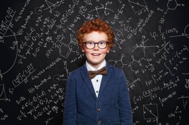 Tahta arka planda okul üniformalı tatlı kızıl saçlı çocuk. 