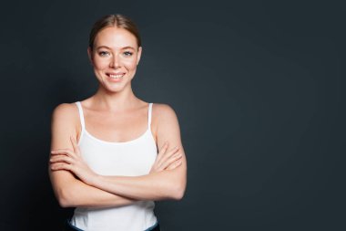 Gri arka planda çapraz kollu mutlu kadın.