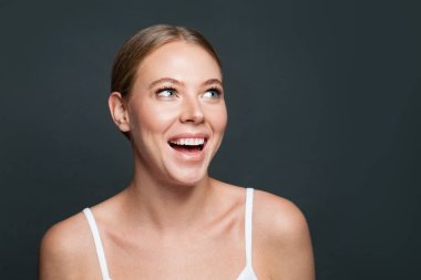 Güzel bir kadın gülüyor ve gri arka plana bakıyor.