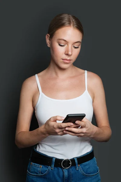 Junge Frau mit Smartphone. Mädchen SMS auf grauem Hintergrund — Stockfoto