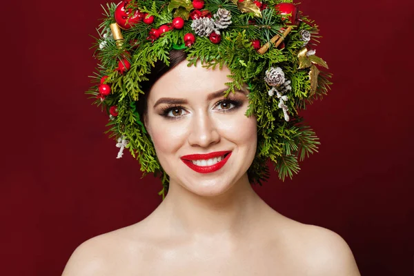 Bella donna che indossa decorazioni natalizie su sfondo rosso — Foto Stock