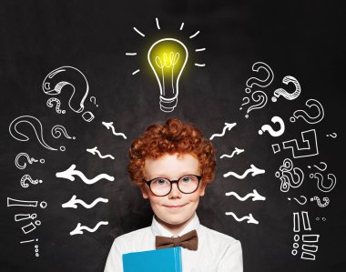 Tahtada soru ve ampulü olan kızıl saçlı çocuk. 