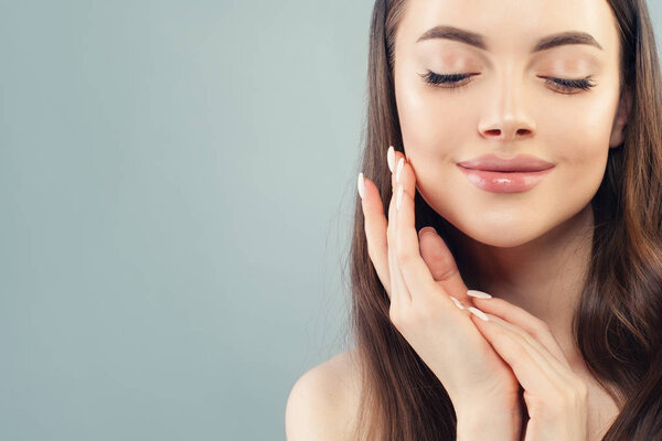 Healthy young woman touching her skin her hand on blue background