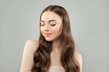 Uzun kahverengi saçlı, gülümseyen güzel bir genç kadın. 