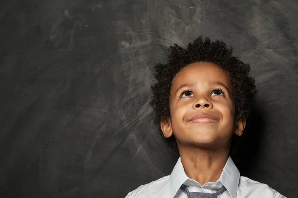 Little child boy looking up on blackboard background — Stock Photo, Image