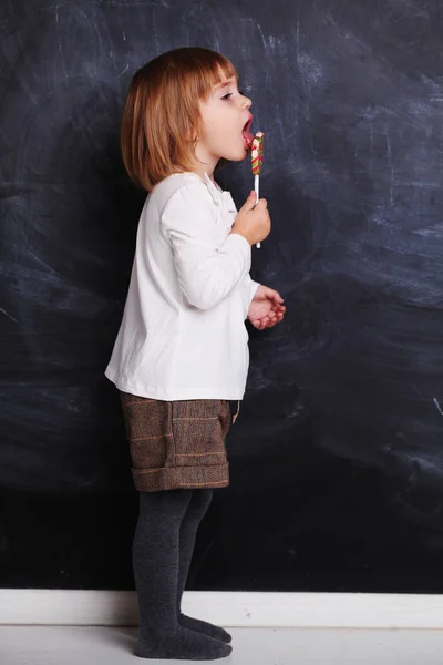 Little girl in white hold lollipop on stick. Little child with s — 스톡 사진