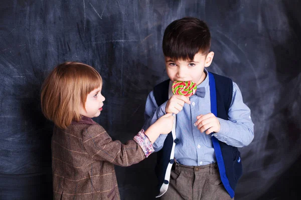 Kleine Syster geeft een broer snoep rode lolly. Jongen en meisje — Stockfoto