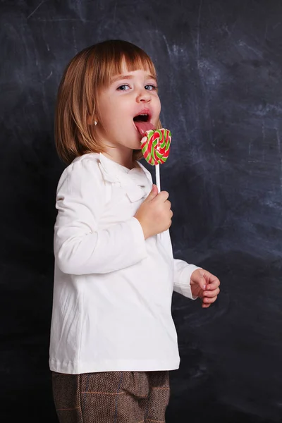 Petite fille tenir une sucette colorée. Petit enfant avec sucette sucrée. Joyeux bonbon. Profiter . — Photo