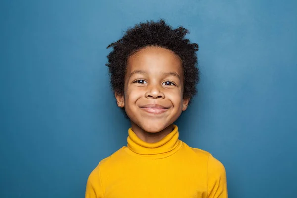 Glückliches Kinderporträt. kleiner afrikanischer amerikanischer Junge auf blauem Grund — Stockfoto