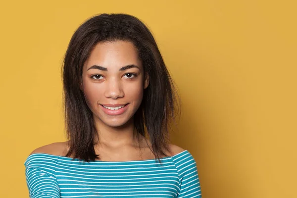 Indoor portrait of beautiful young smiling woman on yellow studio — Stock Photo, Image