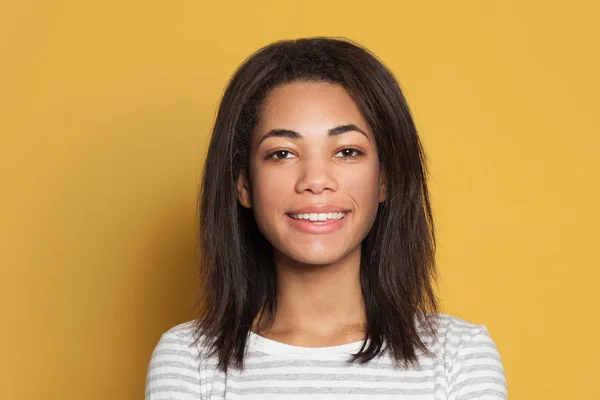 Portret van mooie jonge vrouw glimlachend op gele achtergrond — Stockfoto