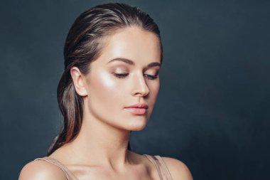 Koyu arkaplanda doğal sağlıklı bir teni olan zarif genç bir kadın.