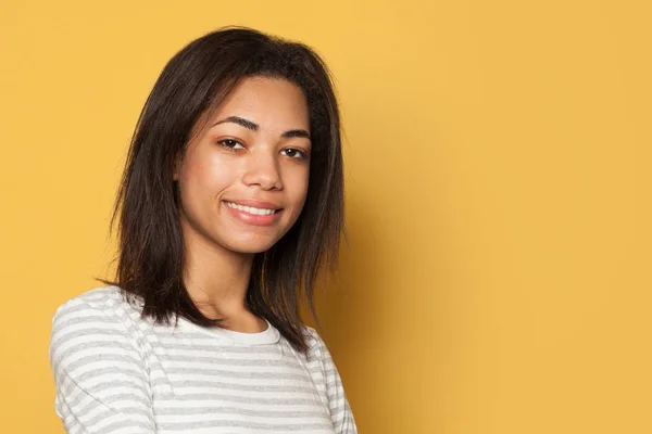 Happy young black woman on yellow studio background — 스톡 사진