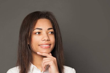 Black girl student thinking on gray background