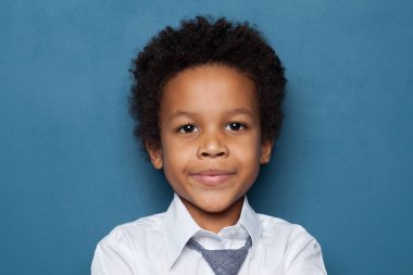 Curious black child schoolboy student portrait on blue background