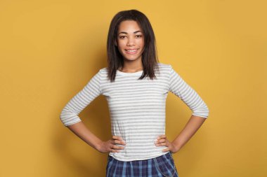 Sarı arka planda gülümseyen melez siyah model kadın.