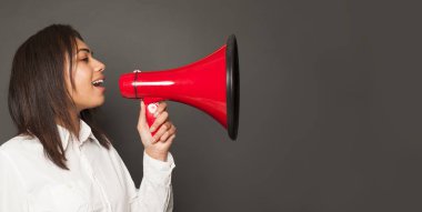 Genç bayan gri arka planda kırmızı hoparlörle konuşuyor.