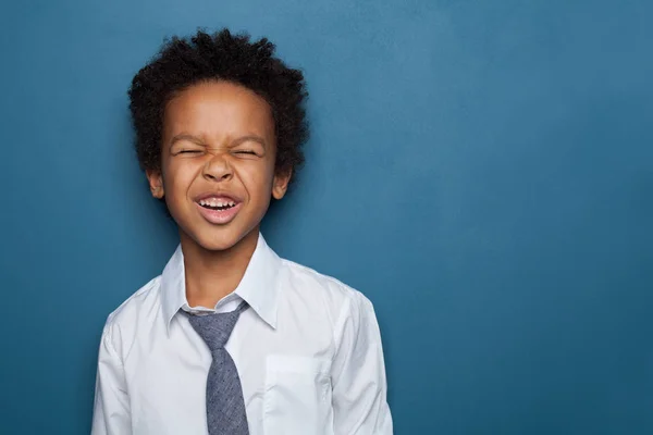Kleiner schwarzer Junge lächelt und blickt auf blauem Hintergrund auf — Stockfoto