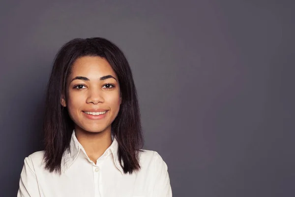Vrolijke jonge zwarte vrouw glimlachen op grijze achtergrond — Stockfoto