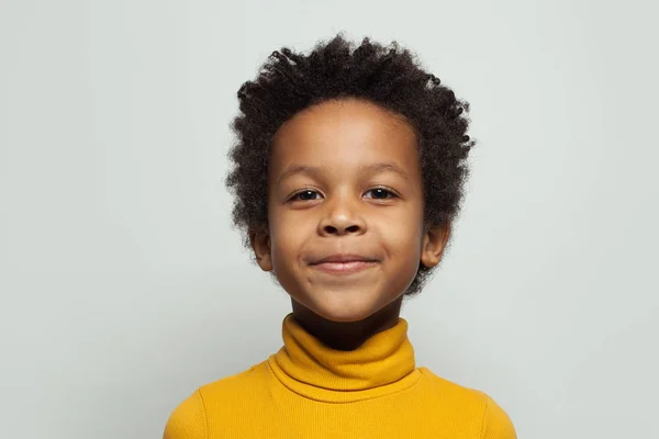 Pequeno menino negro sorrindo no fundo branco, close up retrato — Fotografia de Stock