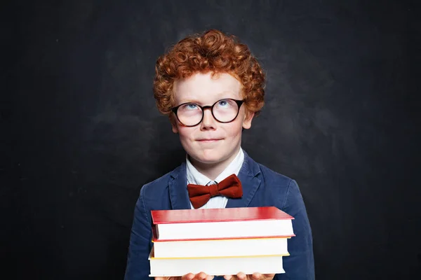 Klein slim kind in blauw studentenuniform met boeken — Stockfoto
