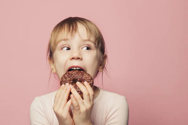 Petite fille drôle avec beignet. sur fond rose — Photo