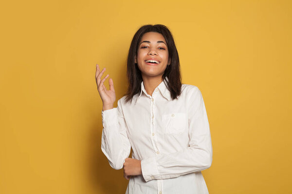 Happy black woman portrait. Beautiful young female model on yellow background