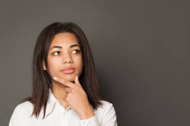 Gri arka planda düşünen zeki siyah kadın.