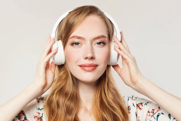 Girl with headphones. Woman listening music on white