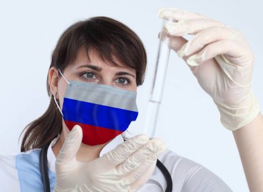 Rus bayrağı taşıyan bilim kadını ve maske. Rusya 'daki bir salgının önlenmesi için laboratuvarda virüs araştırması