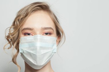 Beyaz arka planda yüz maskesi takan genç bir kadın. Tıbbi maskeli kadın. Grip salgını ve virüs koruma kavramı
