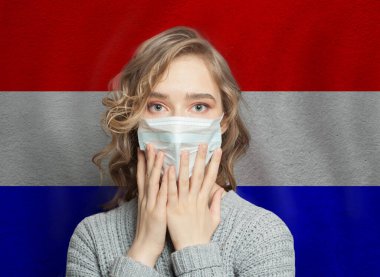 Hollanda bayrağı geçmişinde tıbbi maskeli bir kadın şok oldu. Grip salgını ve aile içi şiddet kavramı